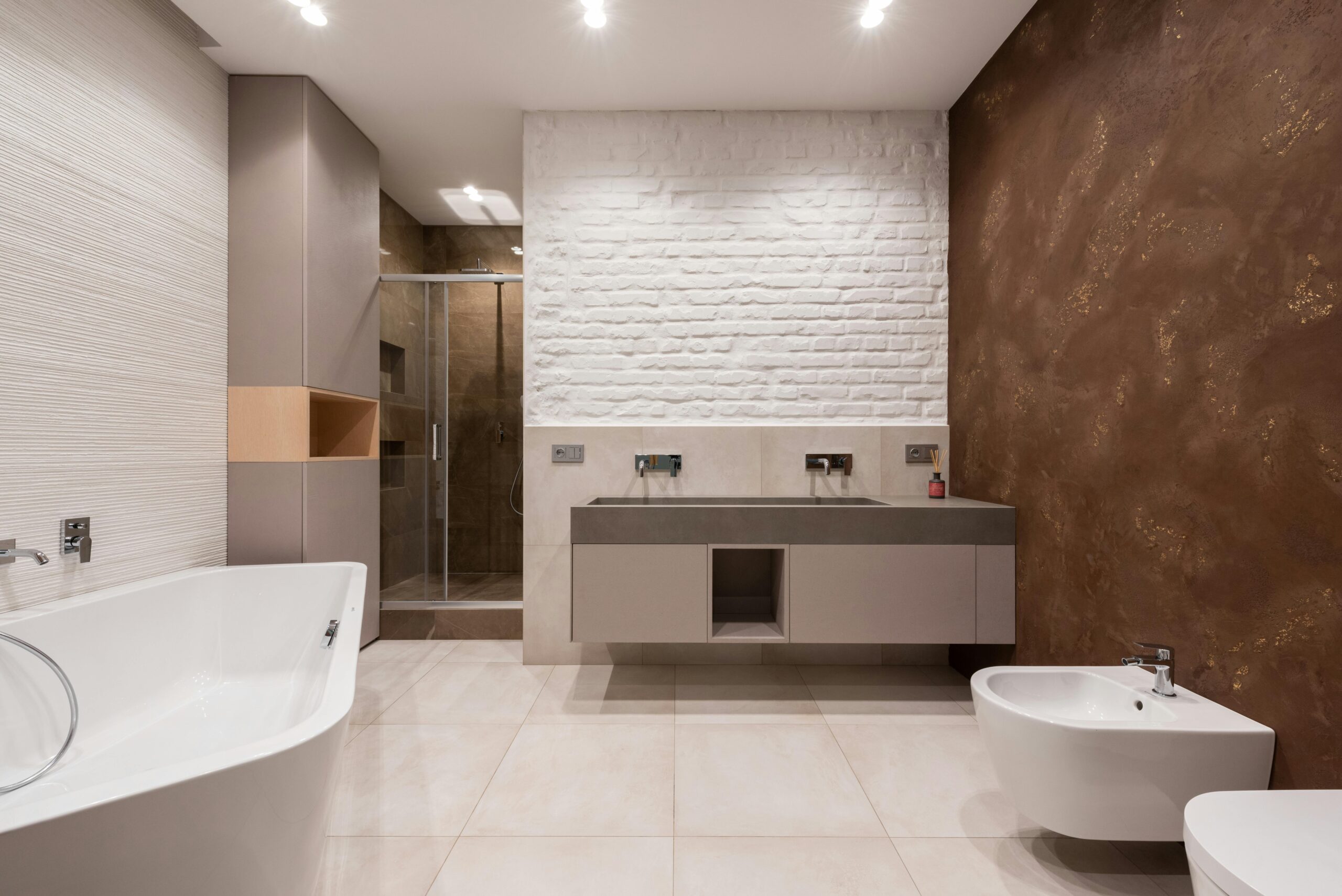 Interior of modern light bathroom with bidet and toilet in front of bath and cabinet with sink and faucet next to shower