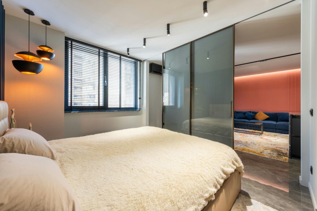 Spacious bedroom featuring modern furnishings and elegant decor with cozy lighting and glass partition.