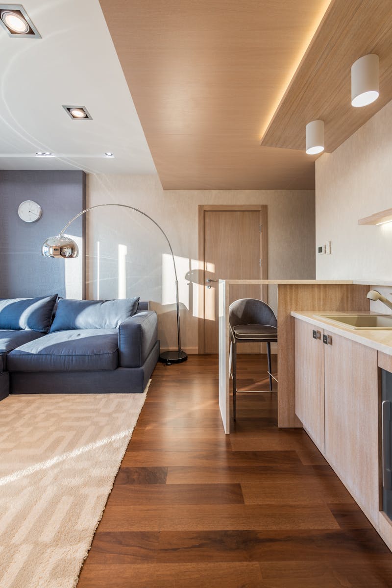 Contemporary living room with open kitchen and modern decor features ample lighting.