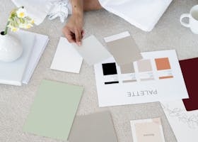 Designer sits on carpet with color palettes and samples, planning creative project.